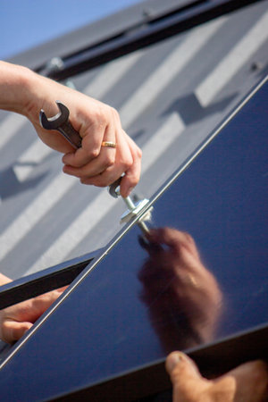 A man is installing solar panels on a roof. Selective focus.の写真素材