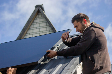 A man is installing solar panels on a roof. Selective focus.の写真素材