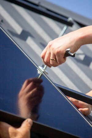 A man is installing solar panels on a roof. Selective focus.の写真素材