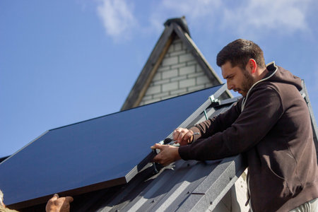 A man is installing solar panels on a roof. Selective focus.の写真素材