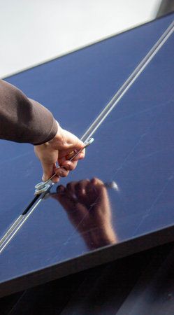 A man is installing solar panels on a roof. Selective focus.の写真素材