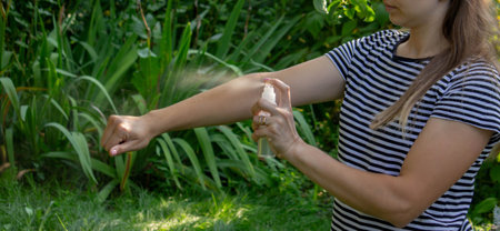 Woman spraying mosquito repellent on arm outdoors in summer garden.の写真素材