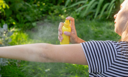 Woman spraying mosquito repellent on arm outdoors in summer garden.の写真素材