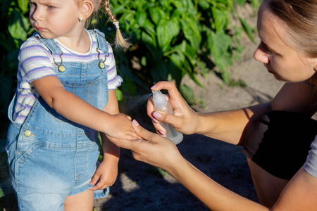 A mother sprays her child with mosquito repellentの写真素材