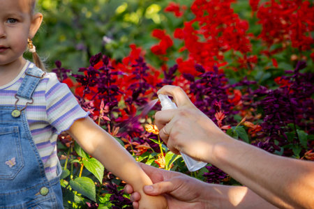Dad sprays his child with mosquito repellent
