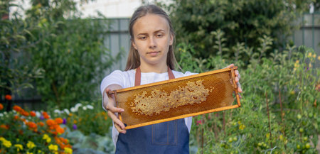 Woman holding a frame with honey on a garden background. Selective focus.