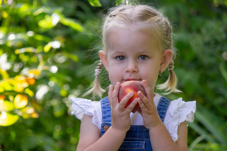 Little girl eating peaches. Selective focus.の写真素材