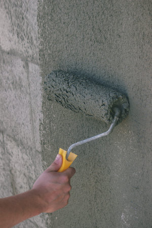 Worker Applying Plaster with Roller.