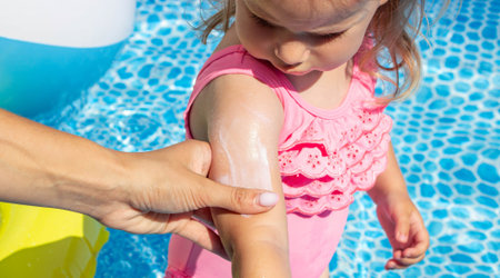 Applying Sunscreen to Child Arm by the Pool.の写真素材
