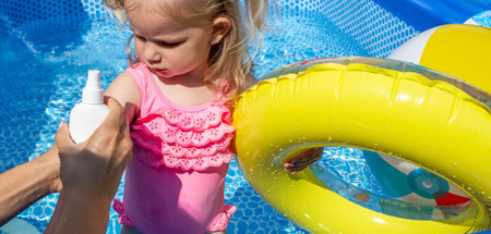 Applying Sunscreen to Child Arm by the Pool.