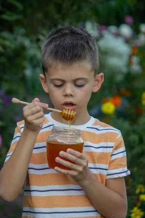 Boy eating honey on a garden background. Selective focus.