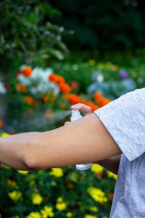 Woman applying insect repellent spray on her hand. Concept of preventing mosquito bites.
