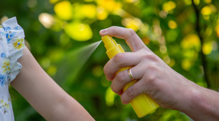 Father insect applying repellent spray to child's hand outdoors. Selective focus.
