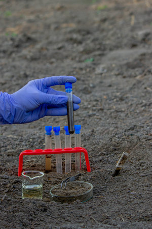 A scientist takes soil into a test tube for analysis. Selective focus