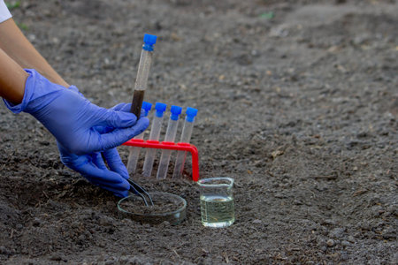 A scientist takes soil into a test tube for analysis. Selective focus