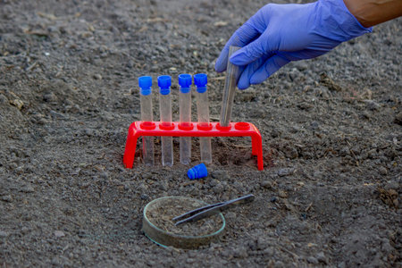 A scientist takes soil into a test tube for analysis. Selective focus