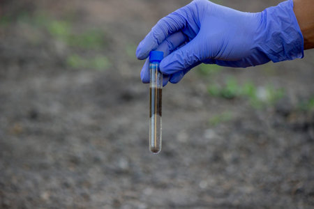A scientist takes soil into a test tube for analysis. Selective focus