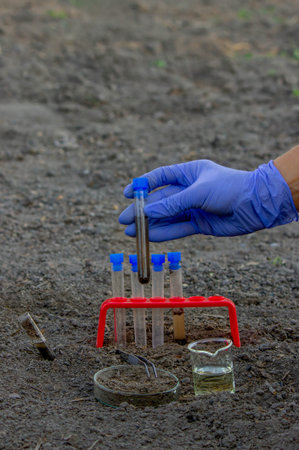 A scientist takes soil into a test tube for analysis. Selective focus
