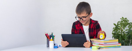 Boy studying remotely. Boy studying with books and his digital tablet at home.
