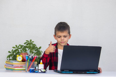 Schoolboy studying online on laptop at home, sitting at table. Distance learning