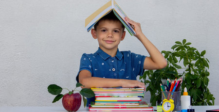 Smiling boy studying with books. School.