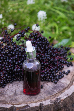 Folk medicine and natural black elderberry syrup on a wooden stump. Elderberry tincture.
