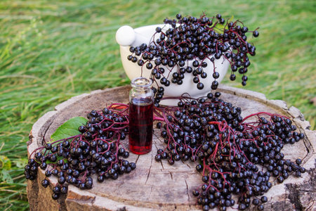 Folk medicine and natural black elderberry syrup on a wooden stump. Elderberry tincture.
