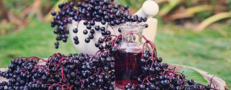 Folk medicine and natural black elderberry syrup on a wooden stump. Elderberry tincture.