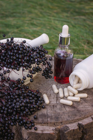 Different forms of natural elderberry medicine. Liquid extract in a bottle and capsules. Immunity.の写真素材