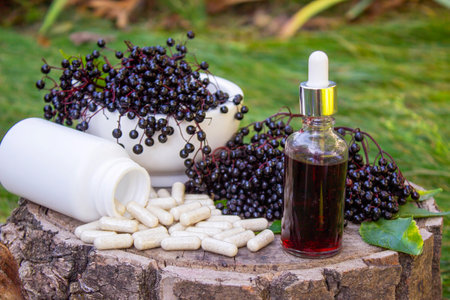 Different forms of natural elderberry medicine. Liquid extract in a bottle and capsules. Immunity.の写真素材