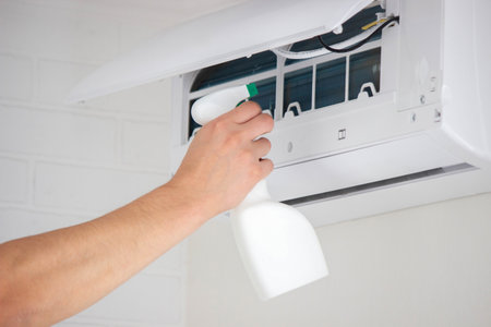 Hands Cleaning the Air Conditioner Unit Filter with a Disinfectant Spray Bottle.の写真素材