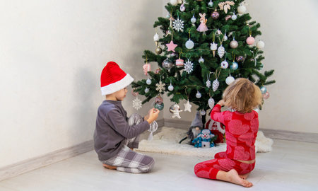 Three children in pajamas decorating a Christmas tree. Christmas Tradition.の写真素材