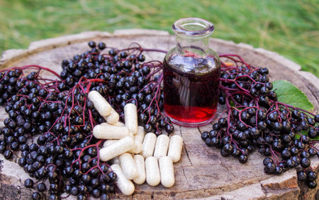 Elderberry berries, syrup and capsules on a wooden stump. Medical propertiesの写真素材
