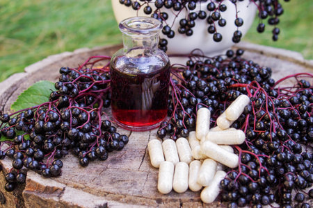 Elderberry berries, syrup and capsules on a wooden stump. Medical propertiesの写真素材