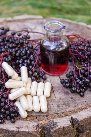 Elderberry berries, syrup and capsules on a wooden stump. Medical propertiesの写真素材