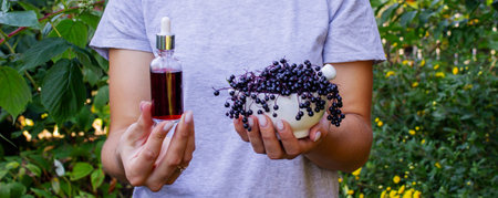 Woman's hands holding elderberry: berries, syrup and capsules. Healthy nutritionの写真素材