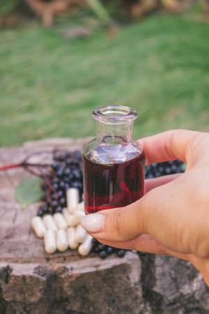 Elderberry berries, syrup and capsules on a wooden stump. Medical propertiesの写真素材