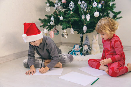 Children writing letters to Santa Claus Saint Nicholas under the Christmas tree.の写真素材