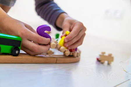 Child playing with a wooden toy train with colorful letters on a light floor