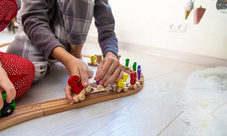 Child playing with a wooden toy train with colorful letters on a light floorの写真素材