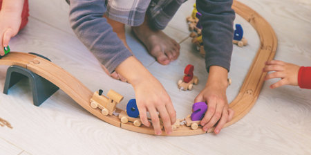 Child playing with a wooden toy train with colorful letters on a light floorの写真素材