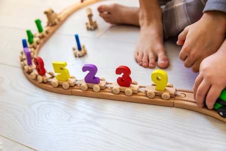Child playing with a wooden toy train with colorful letters on a light floorの写真素材