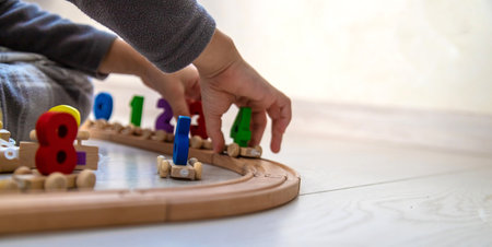 Child playing with a wooden toy train with colorful letters on a light floorの写真素材