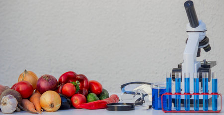 Microscope, test tubes, and fresh vegetables on a lab table for nutritional research.の写真素材