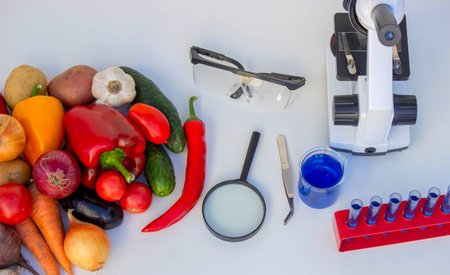 Microscope, test tubes, and fresh vegetables on a lab table for nutritional research.の写真素材