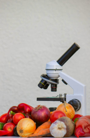 Microscope, test tubes, and fresh vegetables on a lab table for nutritional research.