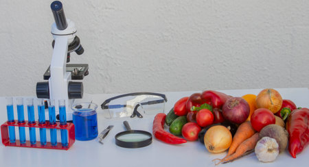Microscope, test tubes, and fresh vegetables on a lab table for nutritional research.の写真素材