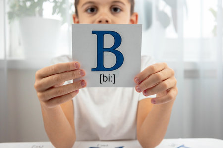 Boy demonstrating a flashcard with the capital letter B and its phonetic transcription.の写真素材