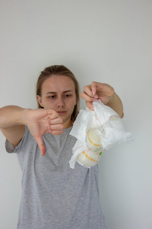 Woman shows thumbs down dislike to disposable diapers, expressing dissatisfaction.