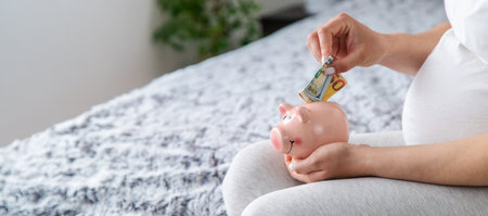 A pregnant woman holds a pig bank in her hands. Selective focus. People.の写真素材